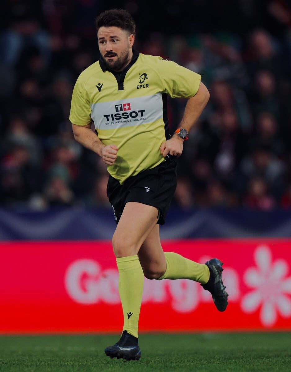 Ben Whitehouse running on the pitch in a yellow match official's shirt
